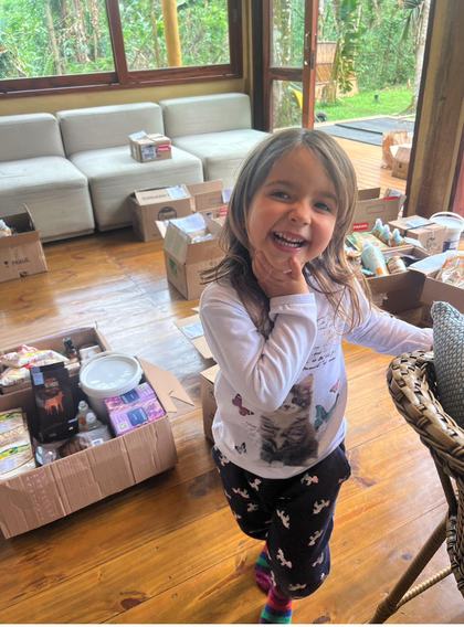 Menina sorrindo em meio às caixas do mutirão de separação
